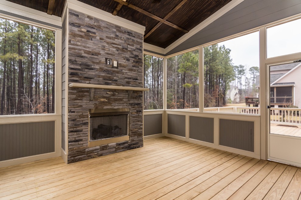 This is an example of a mid-sized country enclosed living room in Raleigh with grey walls, light hardwood floors, a standard fireplace and a stone fireplace surround.