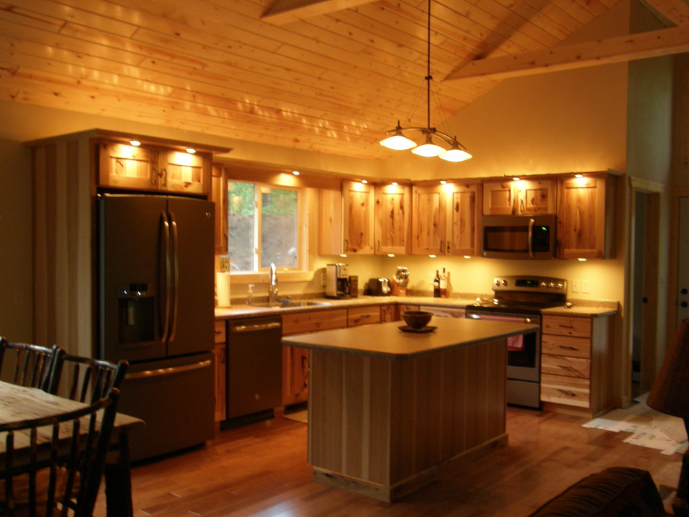 Mid-sized mountain style l-shaped medium tone wood floor open concept kitchen photo with flat-panel cabinets, medium tone wood cabinets, laminate countertops, colored appliances and an island