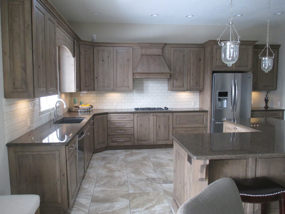 Open concept kitchen - mid-sized transitional l-shaped ceramic tile open concept kitchen idea with an undermount sink, raised-panel cabinets, beige backsplash, subway tile backsplash, stainless steel appliances, an island, medium tone wood cabinets and quartz countertops