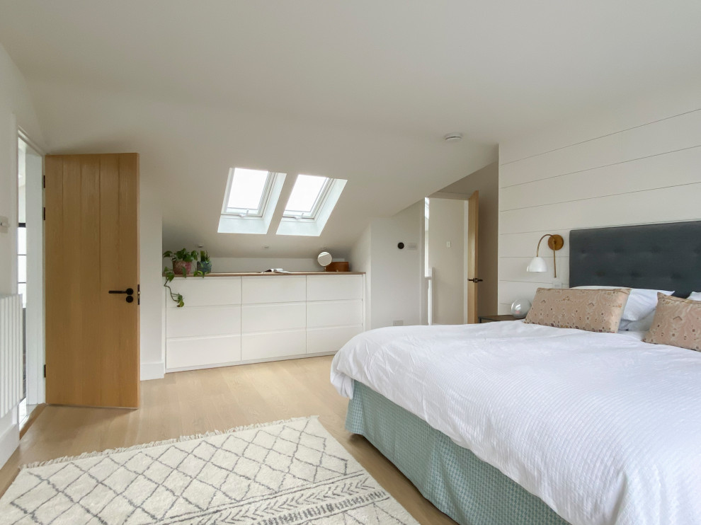 Ejemplo de habitación de invitados escandinava grande con paredes blancas, suelo de madera clara y machihembrado