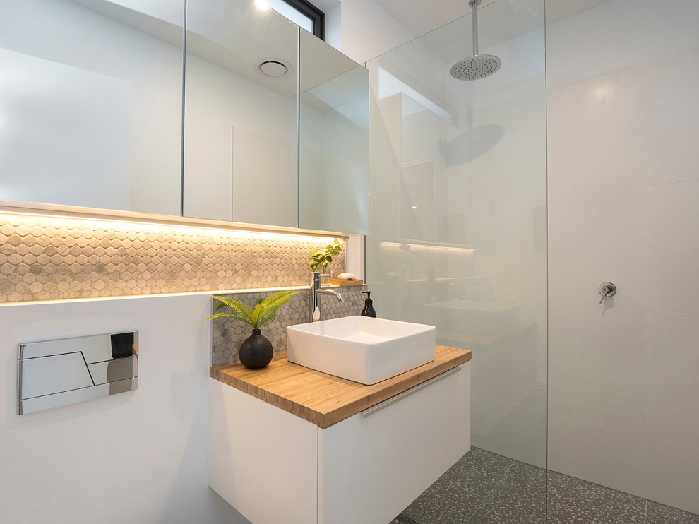 Small contemporary bathroom in Other with white cabinets, white tile, ceramic tile, white walls, terrazzo floors, wood benchtops, an open shower, a curbless shower, grey floor and brown benchtops.