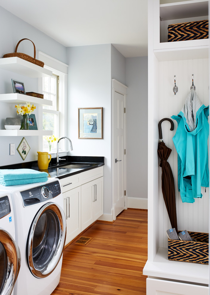 This is an example of a mid-sized transitional l-shaped dedicated laundry room in DC Metro with an undermount sink, recessed-panel cabinets, white cabinets, quartz benchtops, blue walls, medium hardwood floors and a side-by-side washer and dryer.