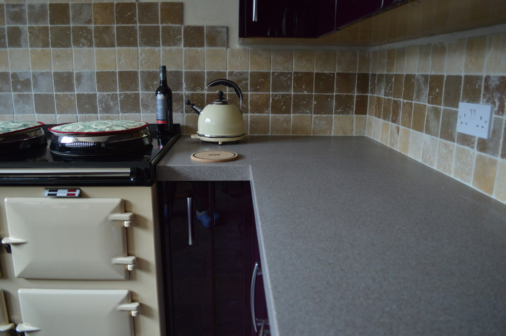 This is an example of a large contemporary galley open plan kitchen in Hampshire with a farmhouse sink, flat-panel cabinets, purple cabinets, laminate benchtops, beige splashback, mosaic tile splashback, coloured appliances and slate floors.