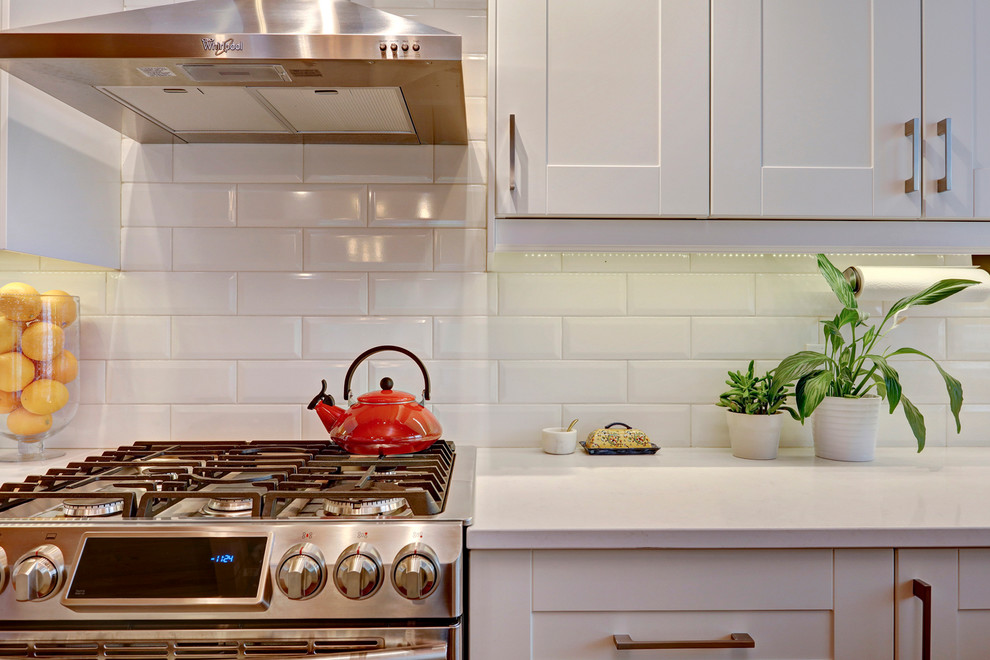 Inspiration for a transitional u-shaped medium tone wood floor eat-in kitchen remodel in Calgary with an undermount sink, shaker cabinets, white cabinets, quartzite countertops, white backsplash, subway tile backsplash, stainless steel appliances and an island