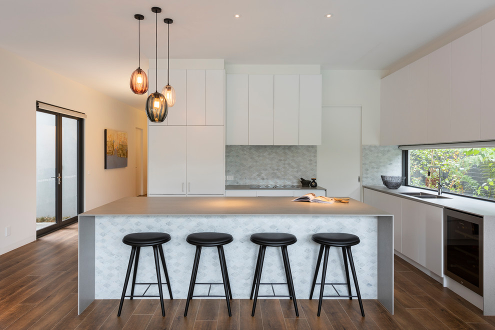 This is an example of a mid-sized contemporary l-shaped open plan kitchen in Melbourne with an undermount sink, flat-panel cabinets, white cabinets, quartz benchtops, multi-coloured splashback, stone tile splashback, stainless steel appliances, porcelain floors, with island, brown floor and multi-coloured benchtop.