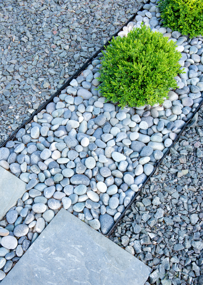 This is an example of a mid-sized mid-century modern full sun front yard stone landscaping in Milwaukee.