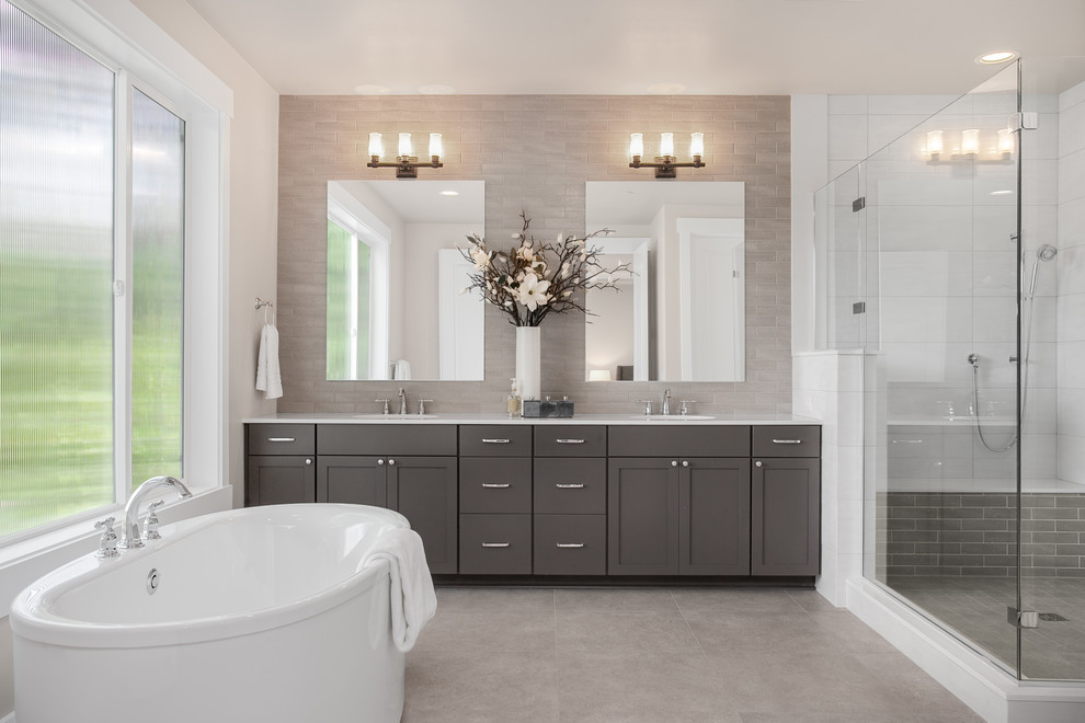 Design ideas for a large arts and crafts master bathroom in Seattle with recessed-panel cabinets, grey cabinets, a freestanding tub, an alcove shower, gray tile, porcelain tile, grey walls, porcelain floors, an undermount sink, engineered quartz benchtops, grey floor, a hinged shower door and white benchtops.