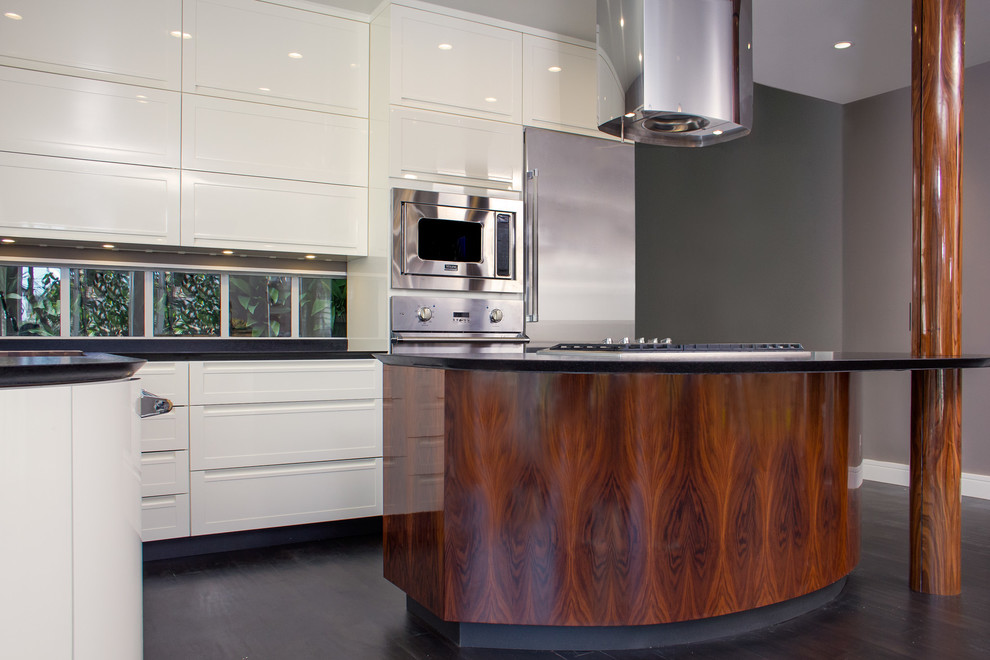 Modern l-shaped eat-in kitchen in San Francisco with an undermount sink, shaker cabinets, white cabinets, solid surface benchtops, black splashback, stone slab splashback, stainless steel appliances and with island.