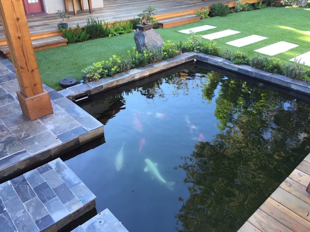 This is an example of a mid-sized asian backyard patio in Los Angeles with a water feature, tile and a pergola.