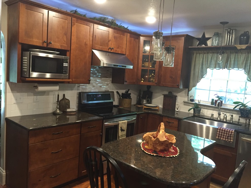 Inspiration for a mid-sized transitional u-shaped enclosed kitchen remodel with a farmhouse sink, shaker cabinets, medium tone wood cabinets, granite countertops, white backsplash, stainless steel appliances and an island
