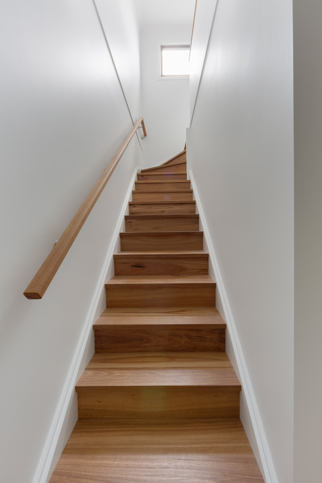 На фото: деревянная лестница в стиле модернизм с деревянными ступенями и деревянными перилами с