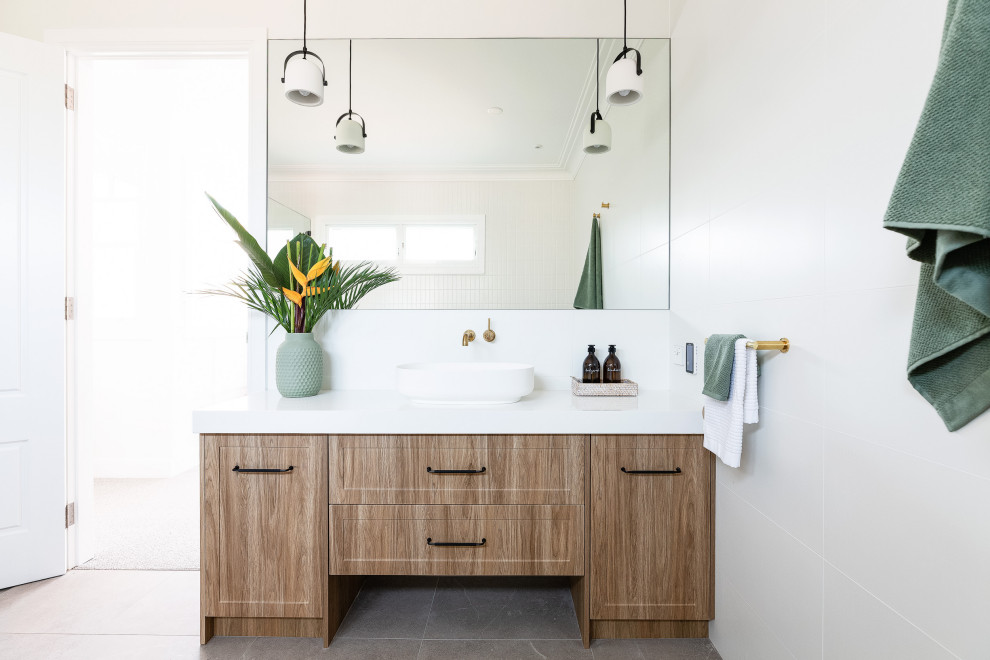 Design ideas for a mid-sized beach style kids bathroom in Sydney with shaker cabinets, a one-piece toilet, white tile, porcelain tile, white walls, porcelain floors, a vessel sink, quartzite benchtops, grey floor, white benchtops, a single vanity, a built-in vanity and medium wood cabinets.