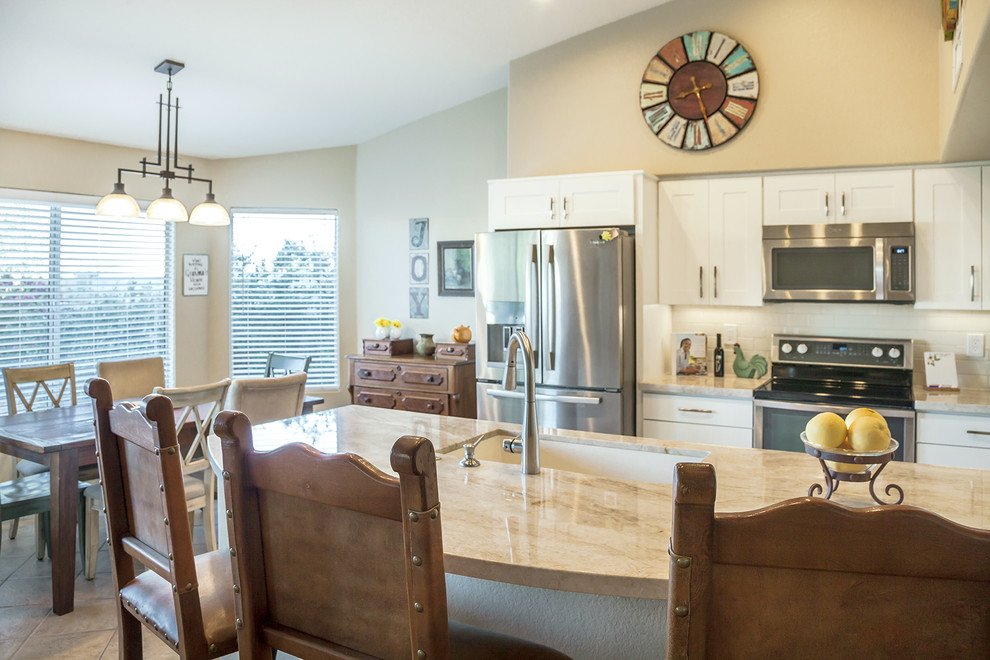 Example of a transitional galley ceramic tile open concept kitchen design in Phoenix with an undermount sink, recessed-panel cabinets, white cabinets, quartz countertops, white backsplash, ceramic backsplash, stainless steel appliances and an island