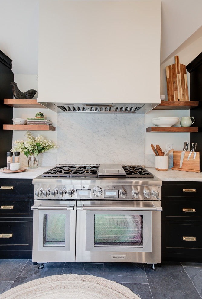 Photo of a mid-sized transitional kitchen pantry in New York with a farmhouse sink, beaded inset cabinets, black cabinets, marble benchtops, white splashback, marble splashback, stainless steel appliances, porcelain floors, a peninsula, white benchtop and coffered.