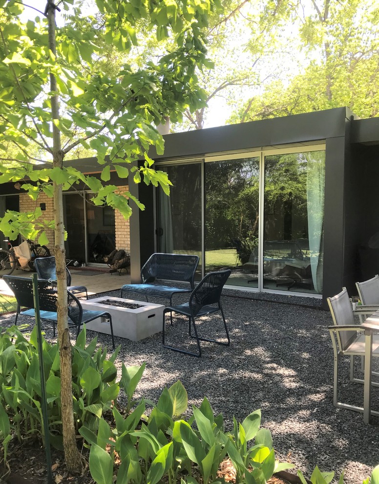 This is an example of a small modern backyard patio in Austin with a fire feature, gravel and no cover.