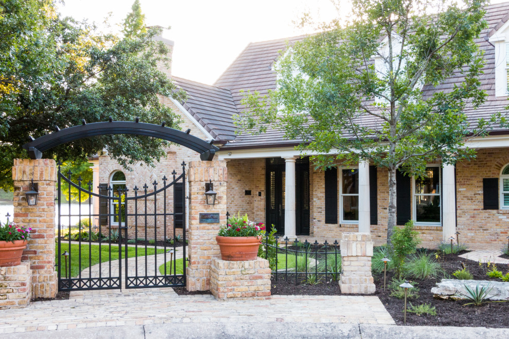 Large traditional front yard partial sun xeriscape in Austin with with a gate, mulch and a metal fence for summer.