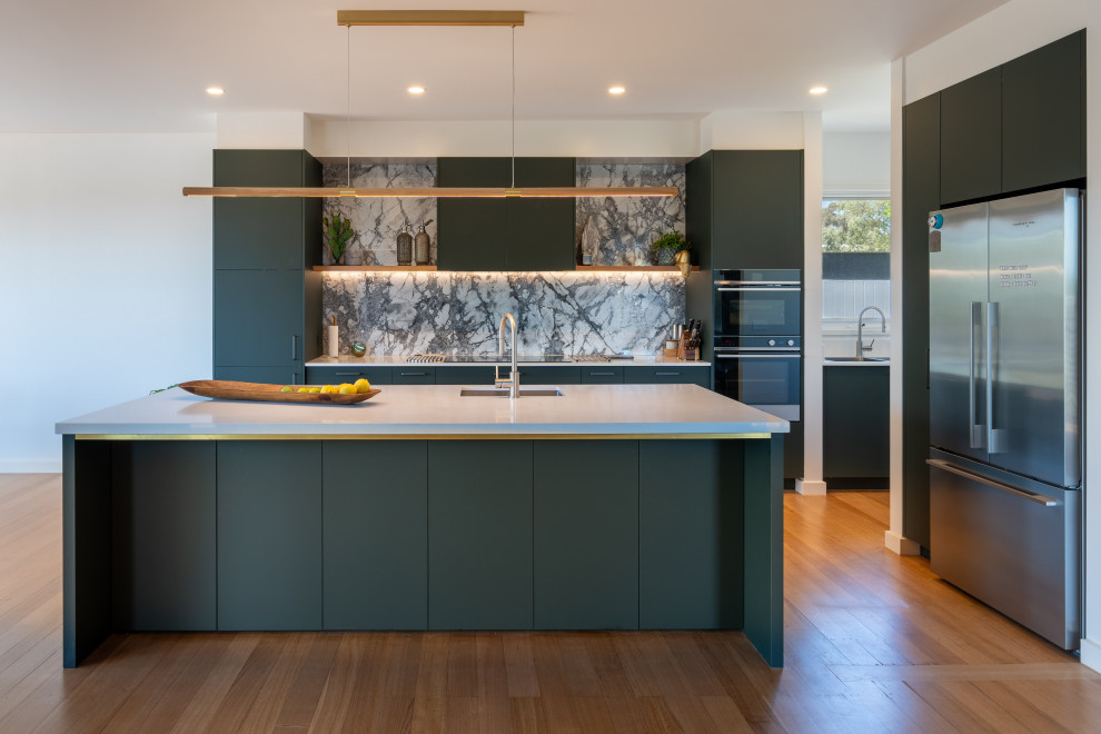 Imagen de cocina contemporánea de tamaño medio con armarios con paneles lisos, puertas de armario verdes, salpicadero de losas de piedra y una isla