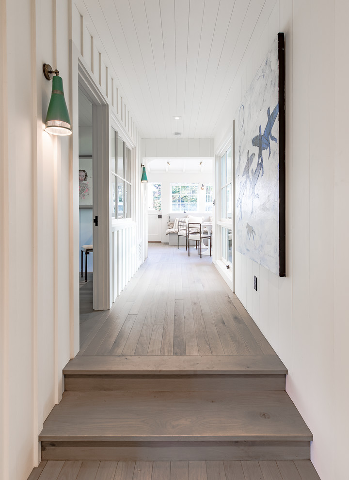 Mid-sized beach style hallway in Santa Barbara with white walls, medium hardwood floors and brown floor.