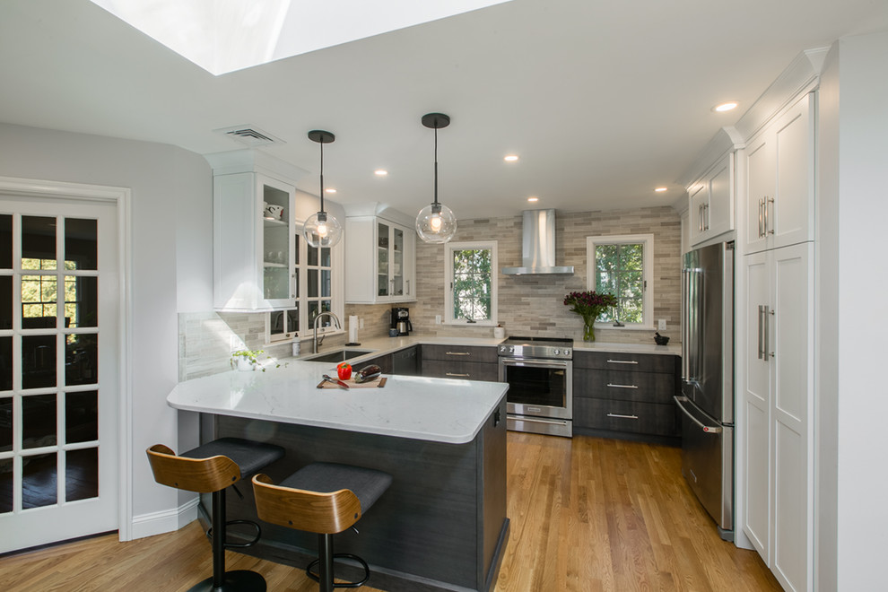 Photo of a mid-sized contemporary u-shaped eat-in kitchen in Boston with an undermount sink, shaker cabinets, white cabinets, quartz benchtops, grey splashback, stone tile splashback, stainless steel appliances, medium hardwood floors, a peninsula and brown floor.