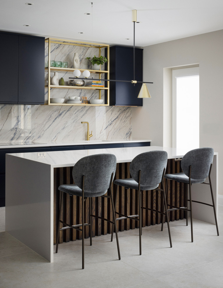Photo of a large contemporary l-shaped kitchen in Dublin with an integrated sink, flat-panel cabinets, blue cabinets, quartzite benchtops, multi-coloured splashback, engineered quartz splashback, panelled appliances, limestone floors, with island, grey floor and white benchtop.