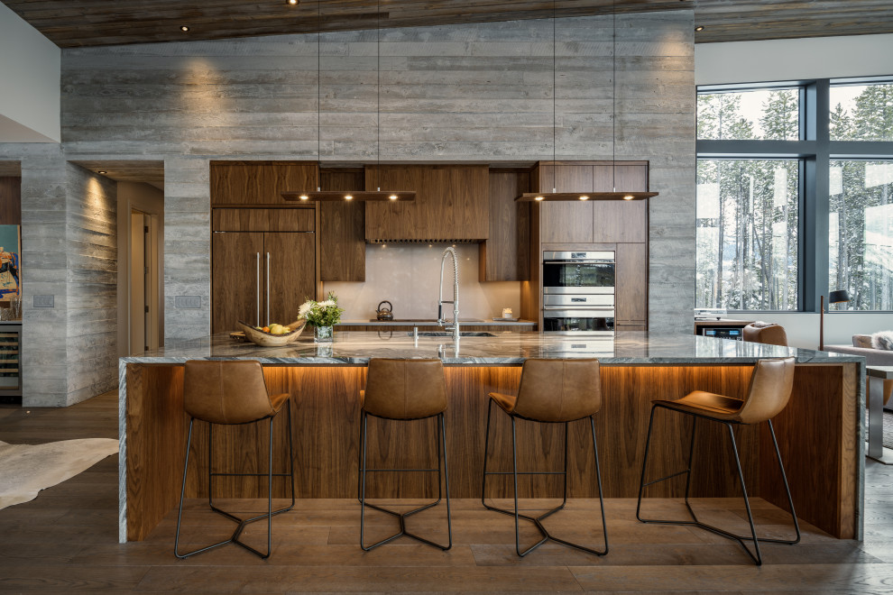 This is an example of a contemporary galley open plan kitchen in Salt Lake City with an undermount sink, flat-panel cabinets, dark wood cabinets, stainless steel appliances, dark hardwood floors, with island, brown floor, grey benchtop, vaulted and wood.
