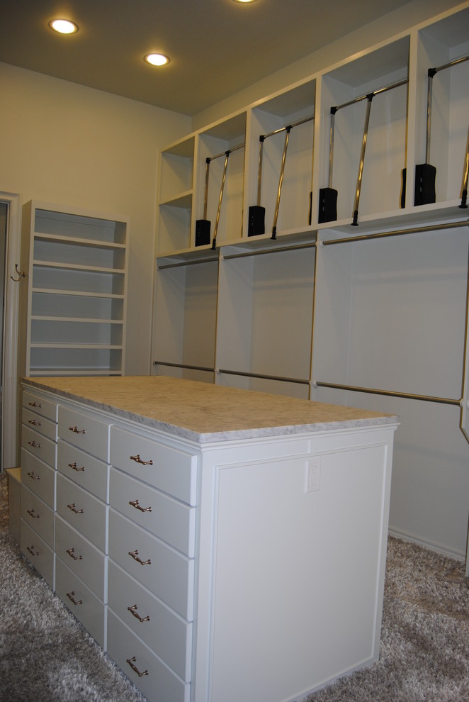 This is an example of a large traditional gender-neutral walk-in wardrobe in Austin with flat-panel cabinets, white cabinets and carpet.