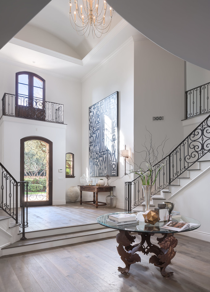This is an example of a mid-sized traditional foyer in Los Angeles with white walls, medium hardwood floors, a single front door, a glass front door and brown floor.