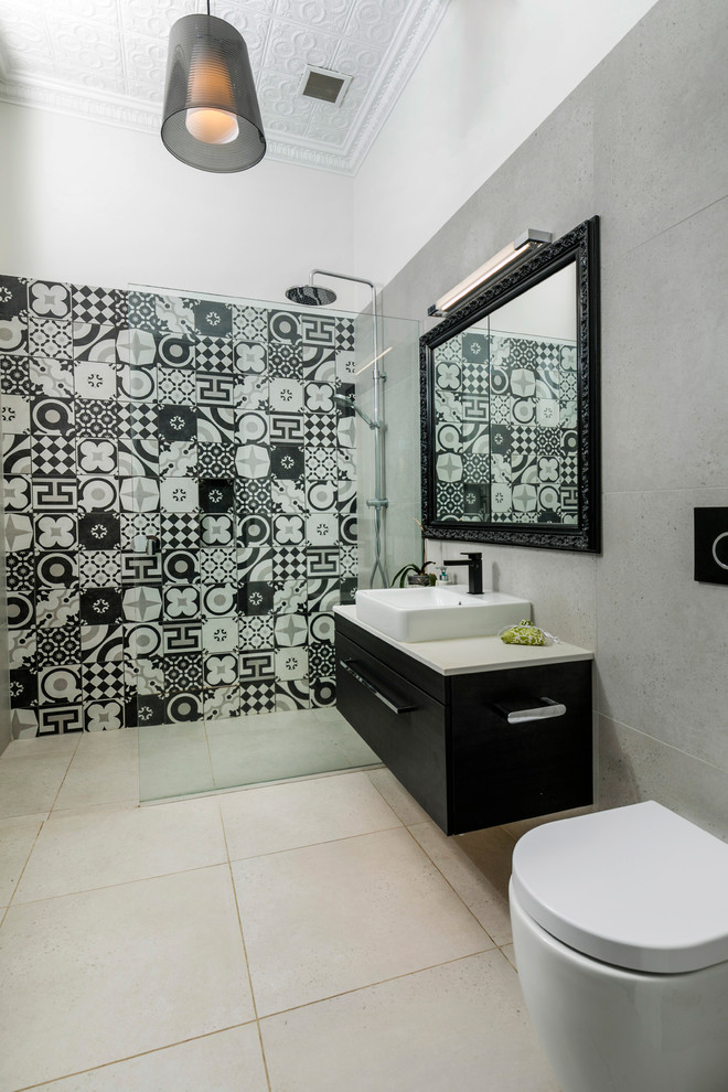 Inspiration for a large contemporary master bathroom in Auckland with flat-panel cabinets, black cabinets, a freestanding tub, a curbless shower, a wall-mount toilet, beige tile, stone slab, white walls, ceramic floors, a vessel sink, engineered quartz benchtops, beige floor and a hinged shower door.