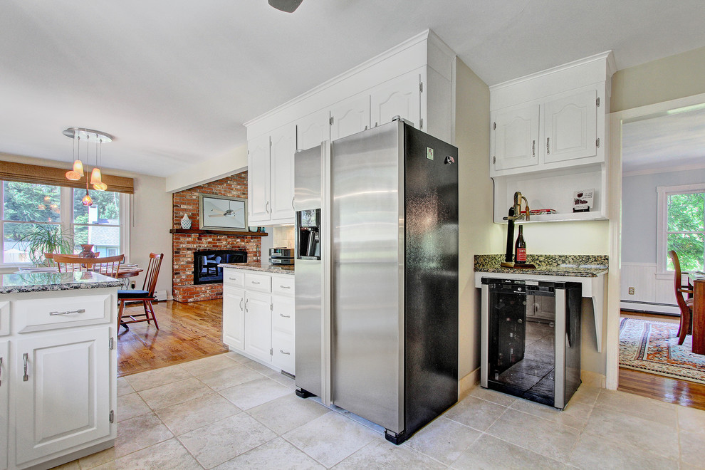Inspiration for a mid-sized transitional u-shaped medium tone wood floor open concept kitchen remodel in New York with an undermount sink, raised-panel cabinets, white cabinets, granite countertops, beige backsplash, ceramic backsplash, stainless steel appliances and an island