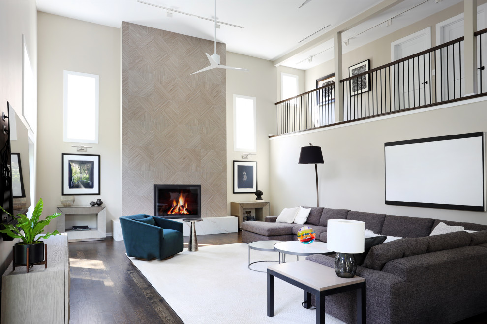 Cette image montre une grande salle de séjour mansardée ou avec mezzanine minimaliste avec un mur beige, parquet foncé, une cheminée standard, un manteau de cheminée en carrelage et un sol marron.