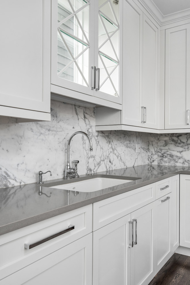 Open concept kitchen - mid-sized transitional l-shaped medium tone wood floor open concept kitchen idea in Chicago with an undermount sink, recessed-panel cabinets, white cabinets, solid surface countertops, white backsplash, stone slab backsplash, white appliances and an island