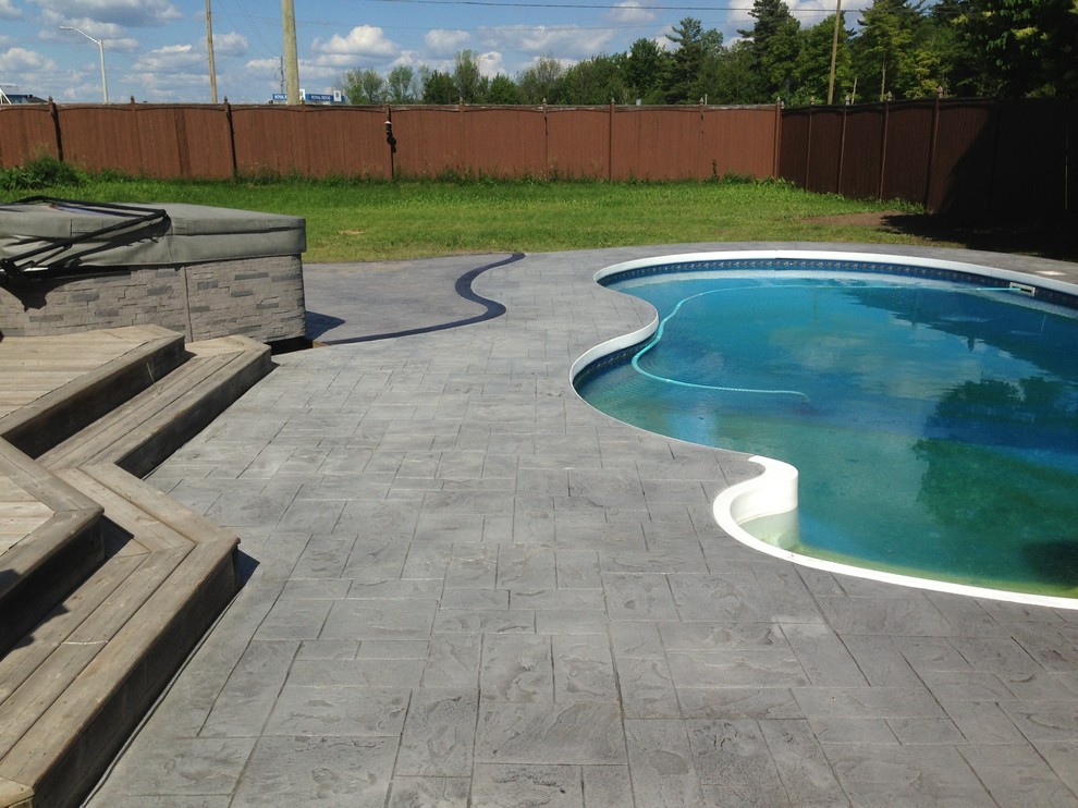 Mid-sized transitional backyard concrete paver and custom-shaped hot tub photo in Ottawa