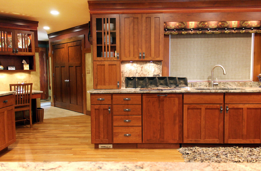 Example of a huge mountain style single-wall light wood floor eat-in kitchen design with an undermount sink, recessed-panel cabinets, medium tone wood cabinets, granite countertops, multicolored backsplash, stone slab backsplash, paneled appliances and a peninsula