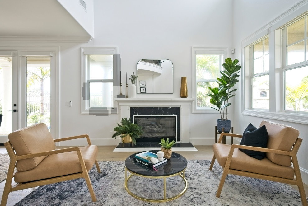 This is an example of a mid-sized beach style living room in Orange County with white walls, light hardwood floors, a stone fireplace surround and beige floor.