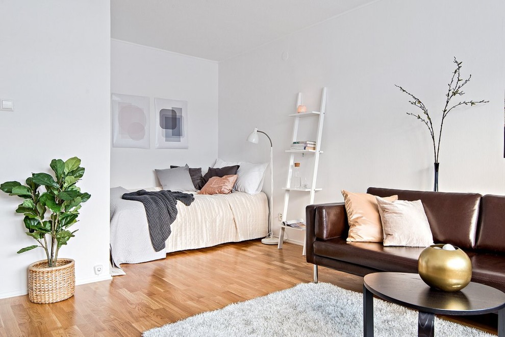 This is an example of a small scandinavian master bedroom in Stockholm with white walls, medium hardwood floors and brown floor.