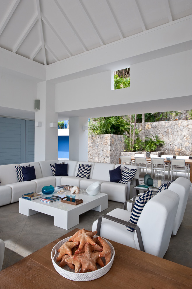 This is an example of a tropical formal open concept living room in Other with white walls and concrete floors.