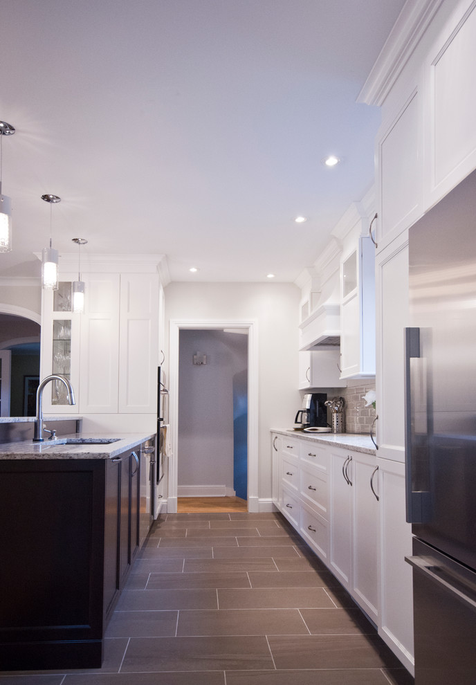 Example of a mid-sized transitional galley ceramic tile eat-in kitchen design in Montreal with an undermount sink, shaker cabinets, white cabinets, granite countertops, beige backsplash, subway tile backsplash, stainless steel appliances and an island
