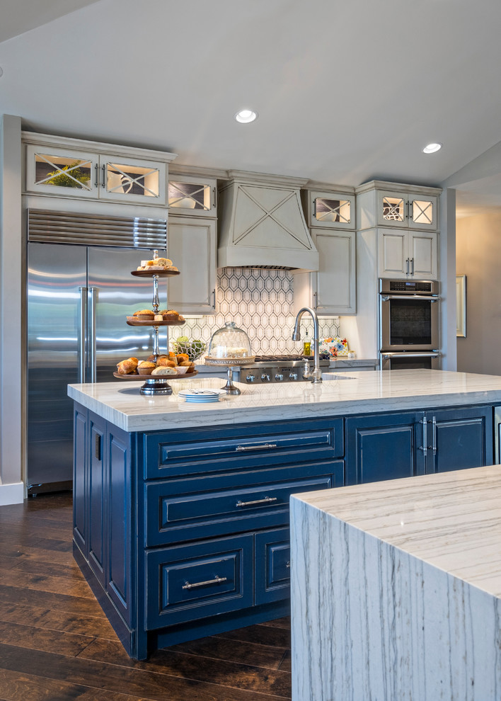 Design ideas for a mid-sized beach style u-shaped open plan kitchen in Miami with a farmhouse sink, raised-panel cabinets, beige cabinets, marble benchtops, stainless steel appliances and multiple islands.