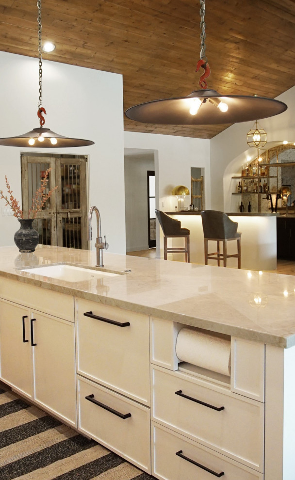 This is an example of a large modern l-shaped open plan kitchen in Phoenix with an undermount sink, shaker cabinets, white cabinets, marble benchtops, beige splashback, marble splashback, stainless steel appliances, medium hardwood floors, with island, brown floor, beige benchtop and wood.