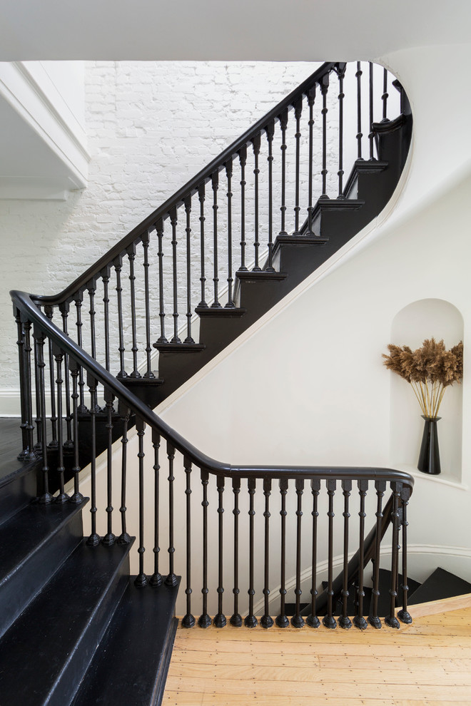 Photo of a large transitional wood u-shaped staircase in New York with wood risers and wood railing.