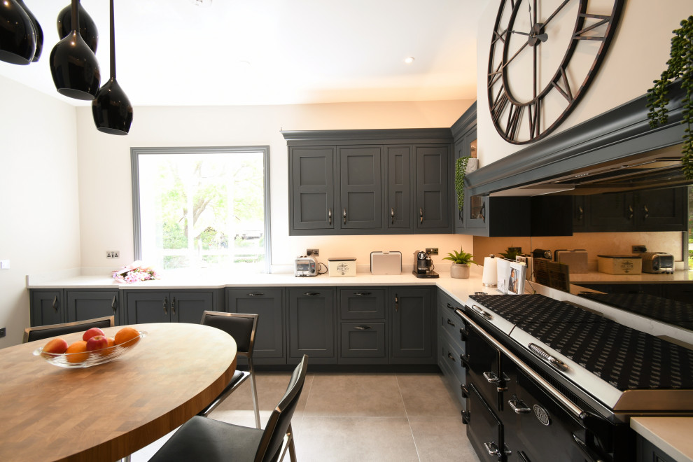 This is an example of a large traditional separate kitchen in Essex with shaker cabinets, quartzite benchtops, glass sheet splashback, a peninsula and white benchtop.