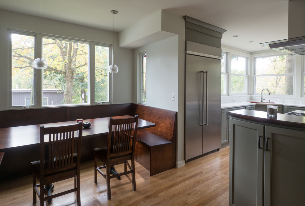 Example of a mid-sized transitional u-shaped medium tone wood floor and brown floor eat-in kitchen design in Cedar Rapids with recessed-panel cabinets, dark wood cabinets, quartz countertops and stainless steel appliances