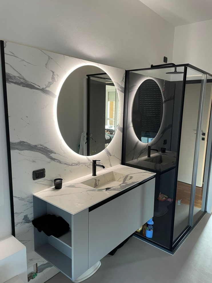 This is an example of a mid-sized modern 3/4 bathroom in Milan with flat-panel cabinets, grey cabinets, a corner shower, a two-piece toilet, white tile, marble, white walls, concrete floors, an integrated sink, marble benchtops, grey floor, a sliding shower screen, white benchtops, a single vanity and a floating vanity.