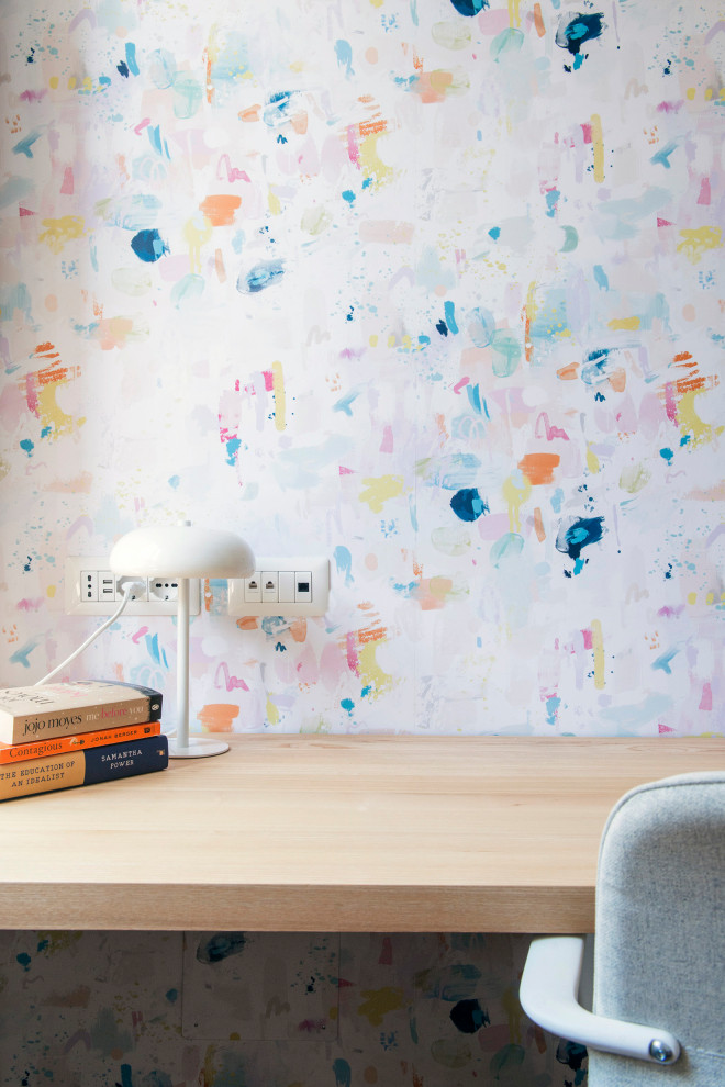 Modelo de despacho minimalista pequeño sin chimenea con paredes blancas, suelo de madera clara, escritorio independiente, suelo marrón y papel pintado