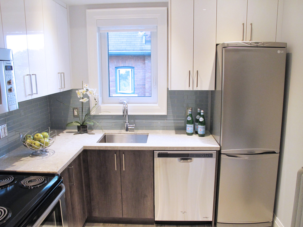 This is an example of a small contemporary l-shaped separate kitchen in Toronto with an undermount sink, flat-panel cabinets, light wood cabinets, quartz benchtops, green splashback, glass tile splashback, stainless steel appliances, light hardwood floors and no island.