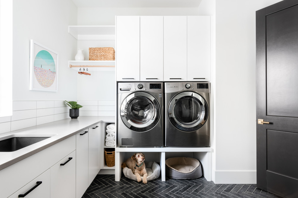 Inspiration for a modern l-shaped ceramic tile and gray floor laundry room remodel in Vancouver with an undermount sink, flat-panel cabinets, quartz countertops, white backsplash, quartz backsplash, white countertops, white cabinets, white walls and a side-by-side washer/dryer
