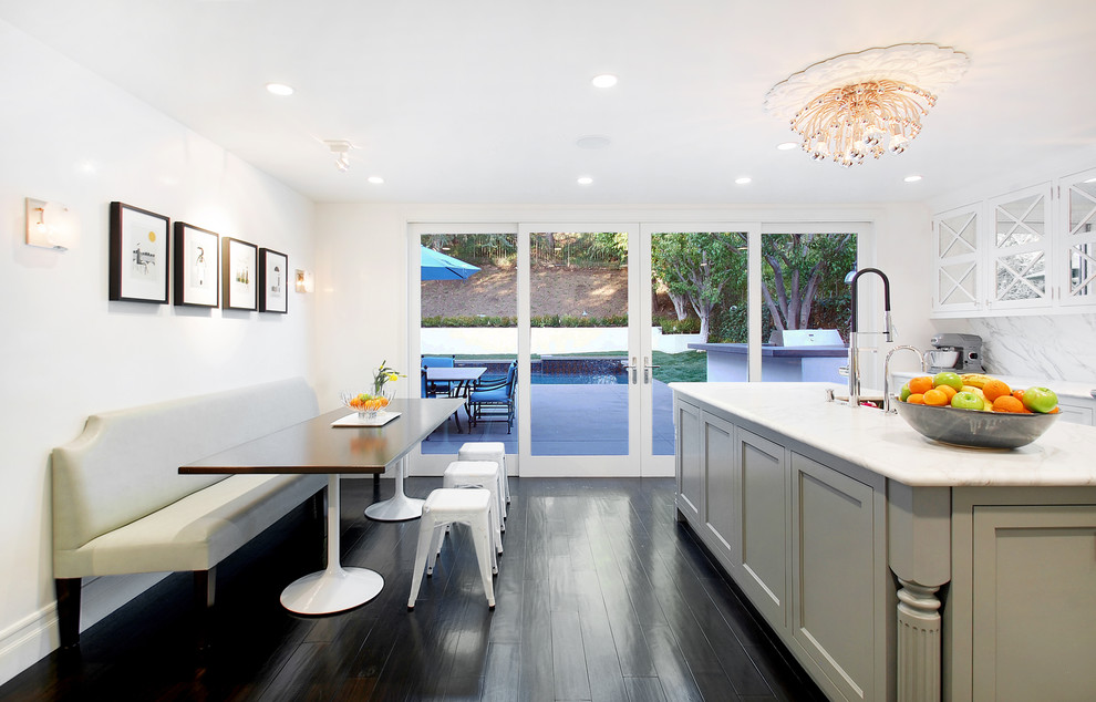 This is an example of a contemporary eat-in kitchen in Los Angeles with glass-front cabinets and white splashback.
