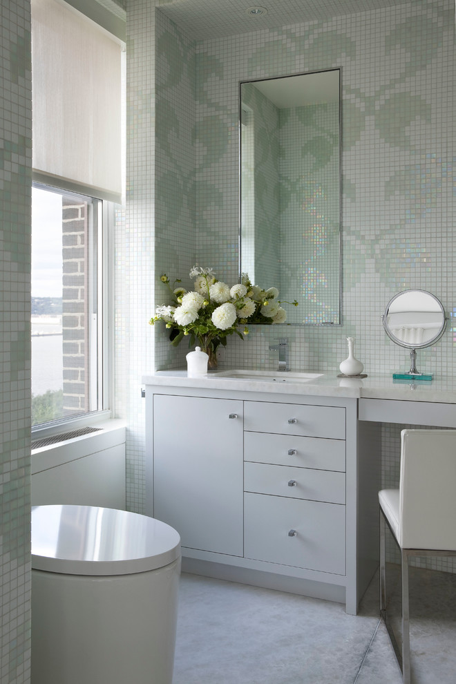 Photo of a contemporary powder room in New York with an undermount sink, flat-panel cabinets, mosaic tile, grey cabinets, green tile and white tile.