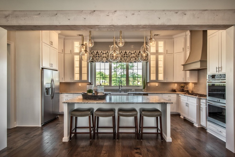 Transitional u-shaped kitchen in Other with a farmhouse sink, shaker cabinets, white cabinets, beige splashback, stainless steel appliances, dark hardwood floors, with island, brown floor and grey benchtop.