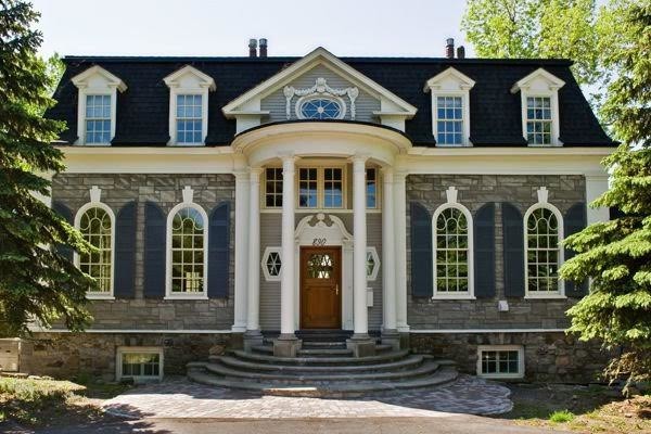 Photo of a large traditional two-storey grey house exterior in Montreal with stone veneer.